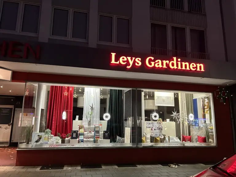 Schaufenster von Leys Gardinen an der Horster Straße 27 in Gelsenkirchen-Buer am Abend mit Vorhängen, Gardinen und Sonnenschutz-Mustern